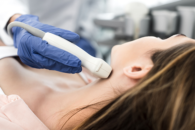 doctor examining thyroid of female patient with ultrasound scan